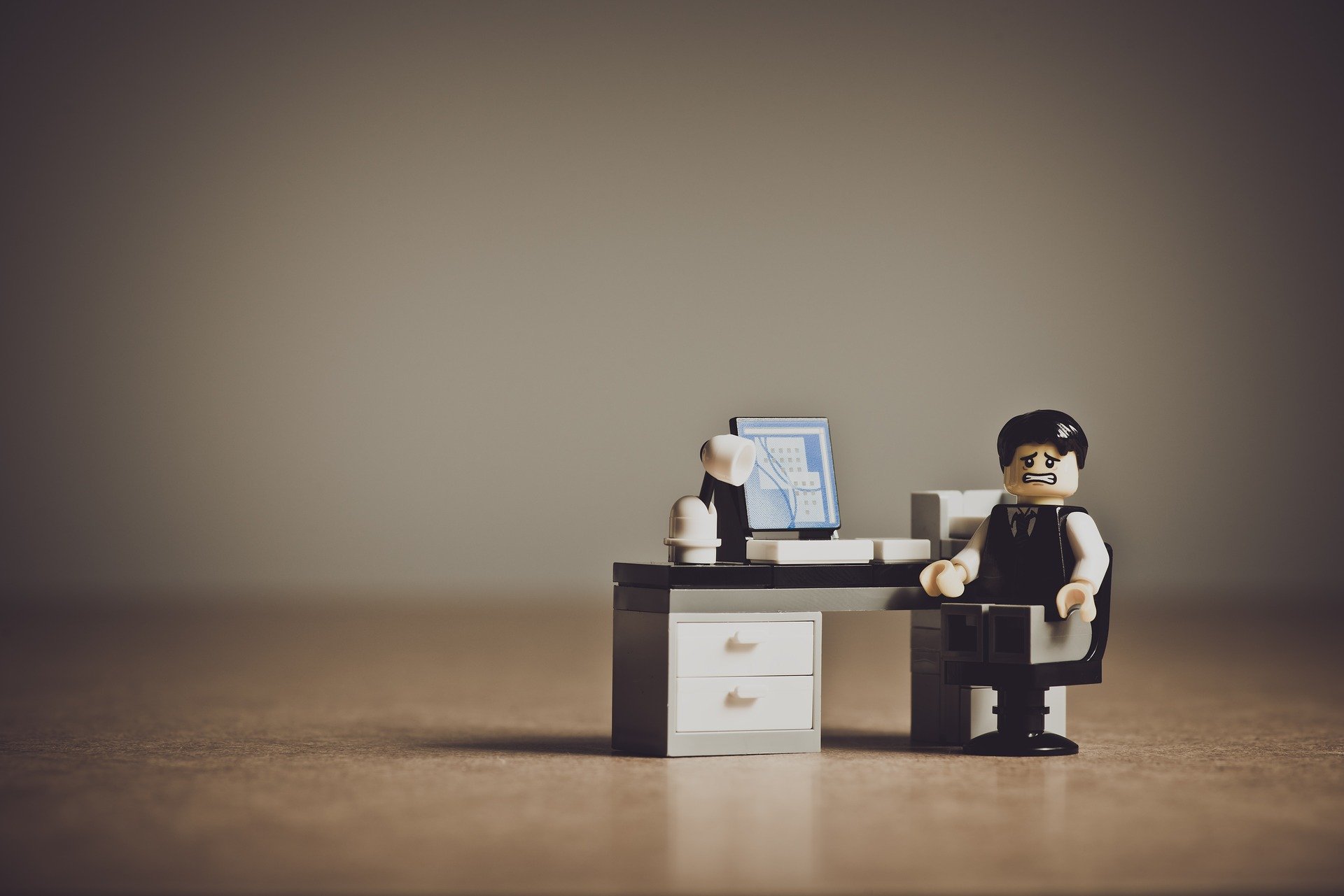 Eine verzweifelte Lego-Figur an einem Schreibtisch mit Computer