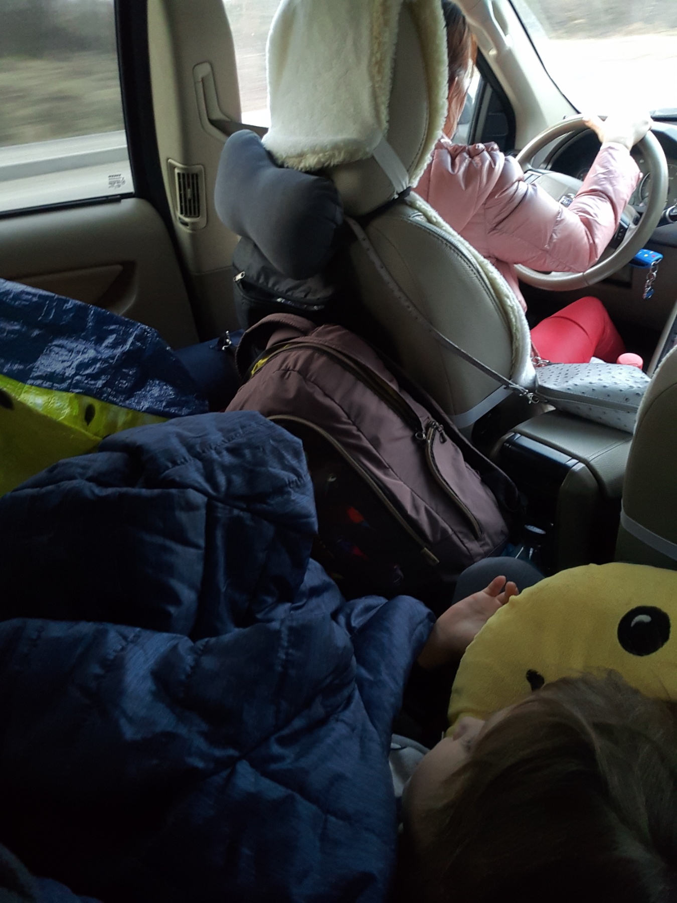 Das Innere eines Autos, auf der vollgepackten Rückbank, ein kleiner Junge schläft