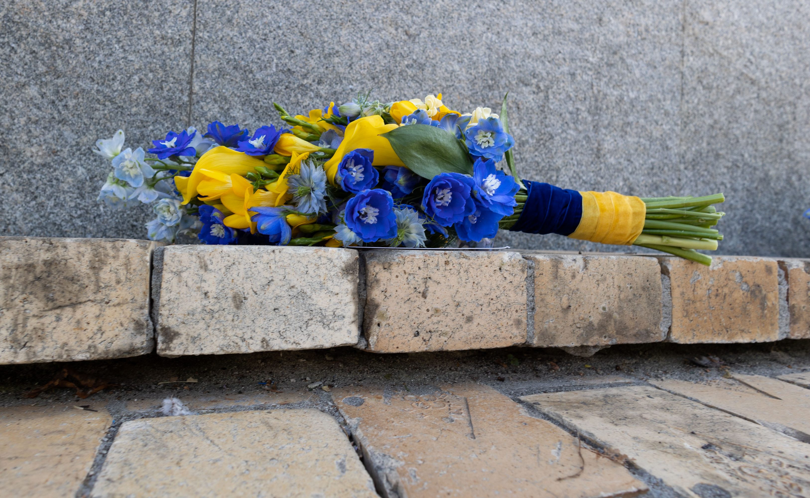 Blau-gelber Blumenstrauß, abgelegt vor einer Gedenkmauer, am Ukrainischen Unabhängigkeitstag 2022
