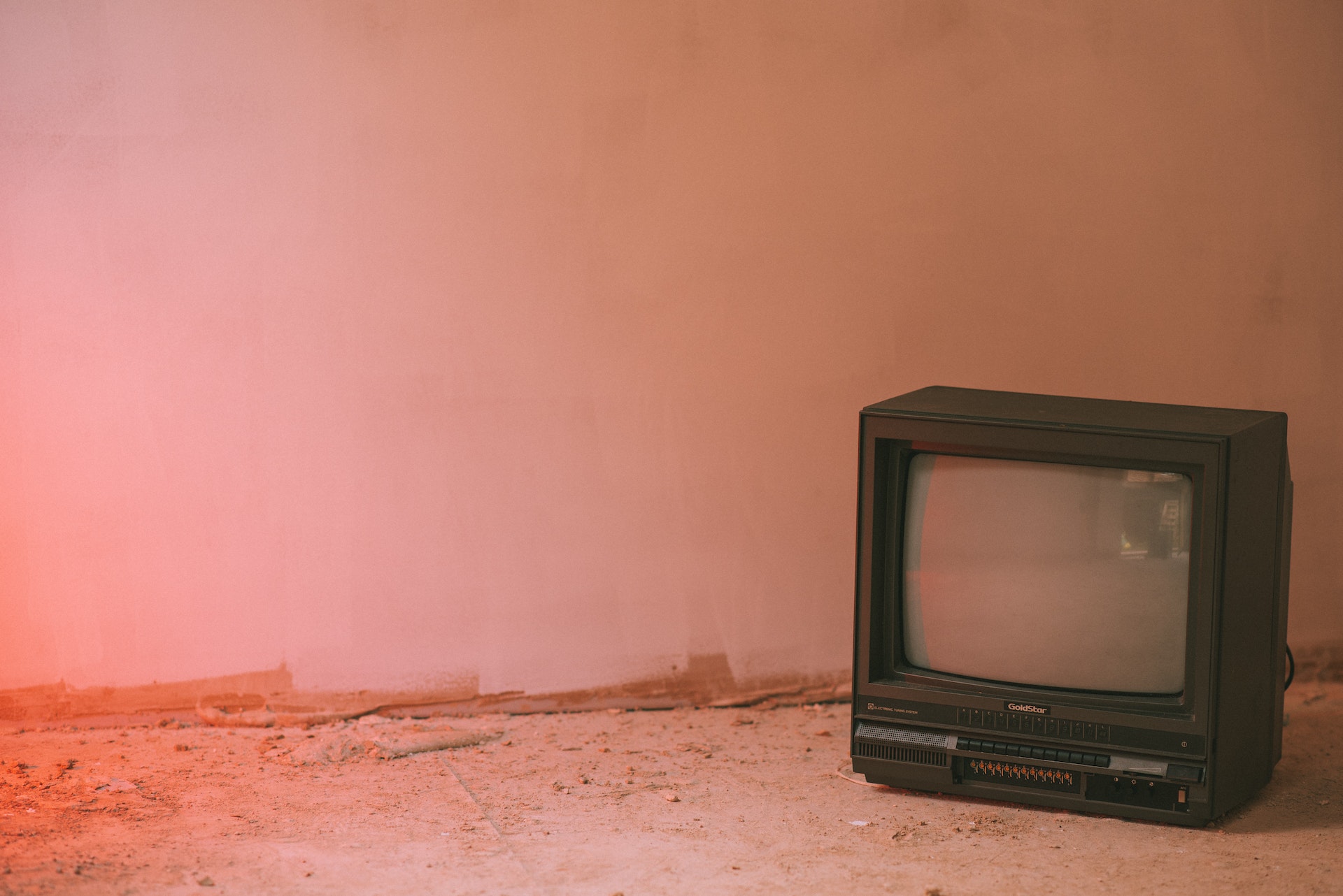 Ein alter Röhren-Fernseher vor einem pastell-rosa Hintergrund